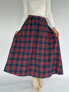 Person wearing a red and blue plaid skirt on a white background