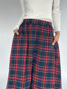 Plaid skirt worn with a white sweater on a plain background showing elastic waist and side pockets