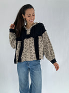 Woman wearing a black and floral-patterned hoodie top with blue jeans on a white background