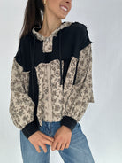 Woman wearing a black and beige floral top with blue jeans on a white background