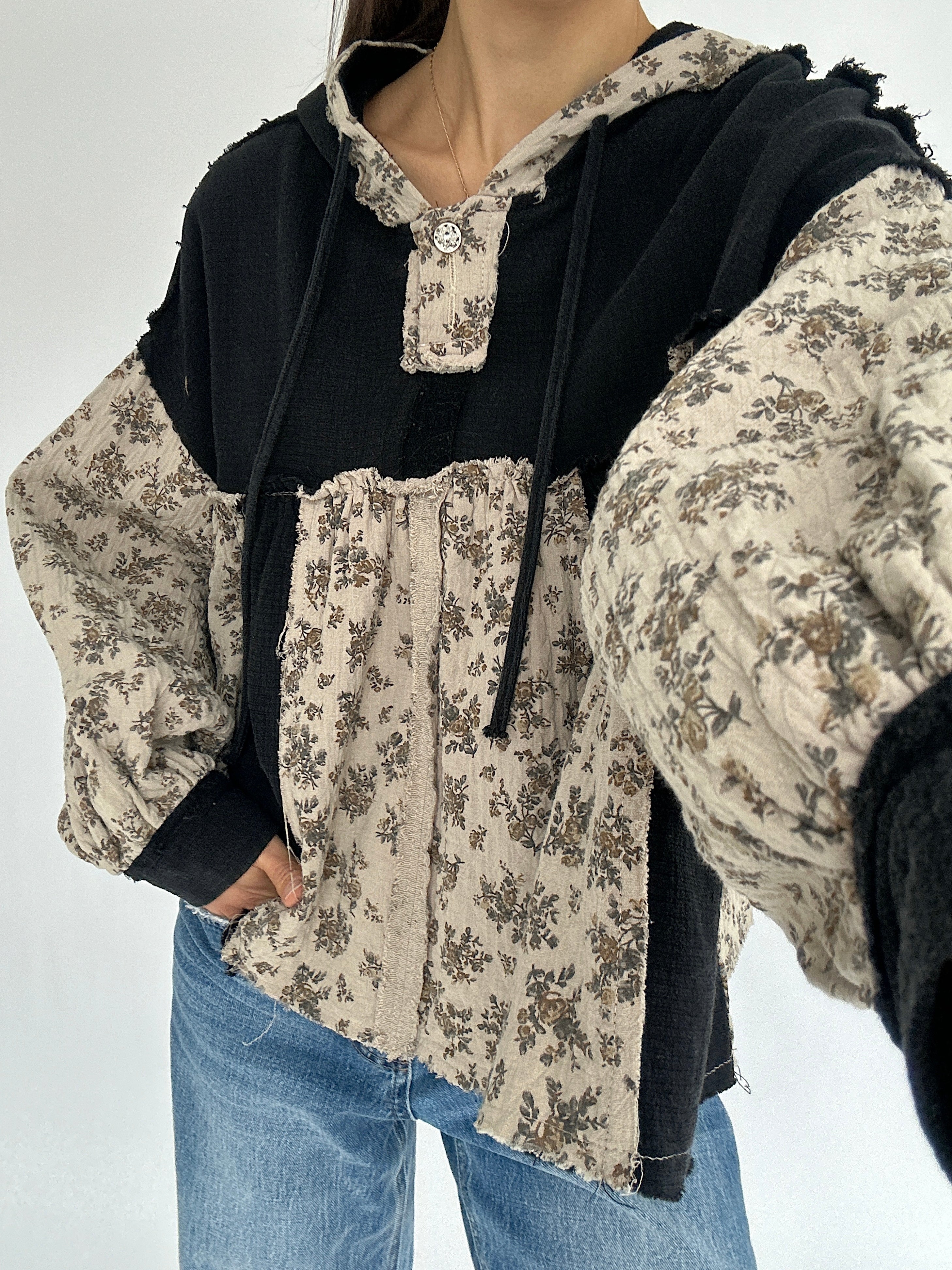 Floral patterned shirt with black hood on a plain background