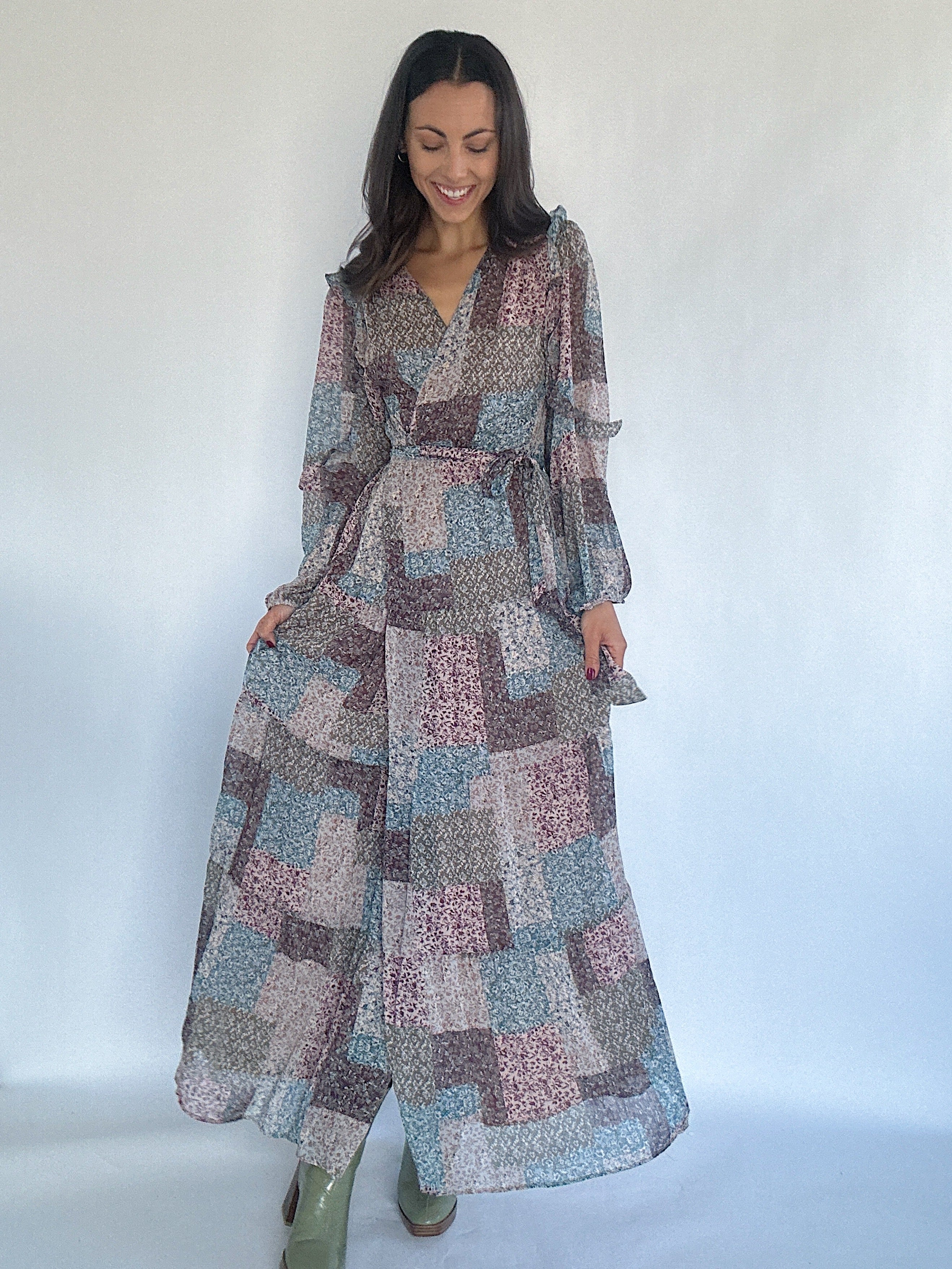 Woman wearing a long, patchwork patterned dress against a white background