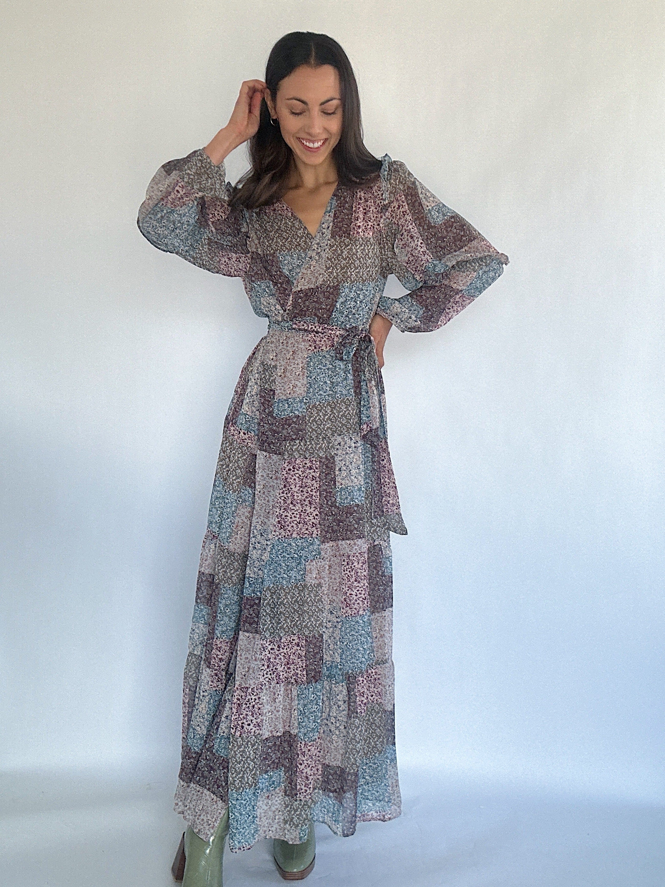 Woman wearing a patchwork patterned wrap maxi dress against a white background