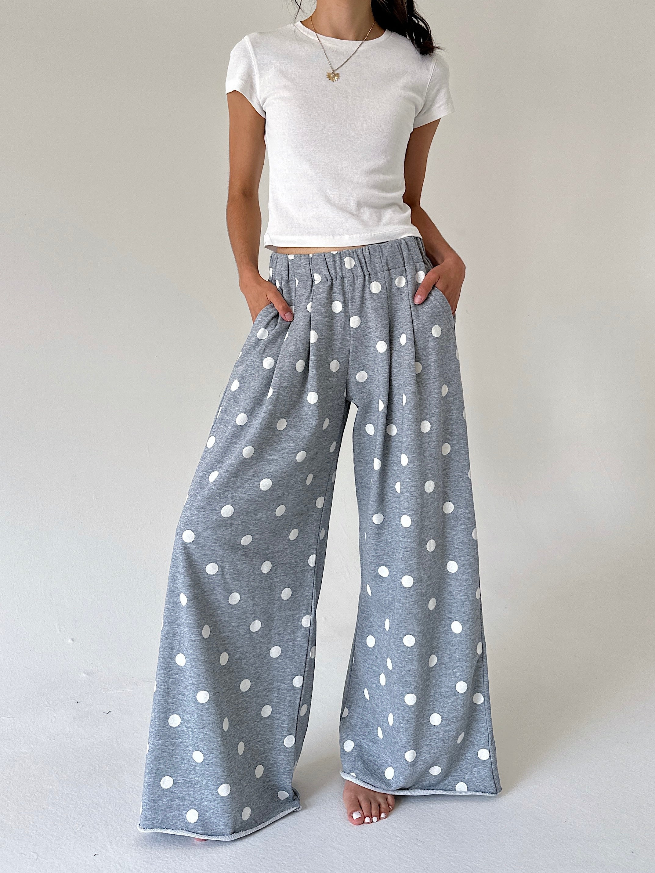 A model wearing wide-leg lounge pants in heather gray with a white polka dot pattern, styled with a white t-shirt against a neutral studio background.