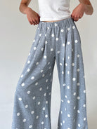 A person wearing loose, wide-leg lounge pants in heather gray with a white polka dot pattern, paired with a white tank top, shown from the waist down against a plain light background.