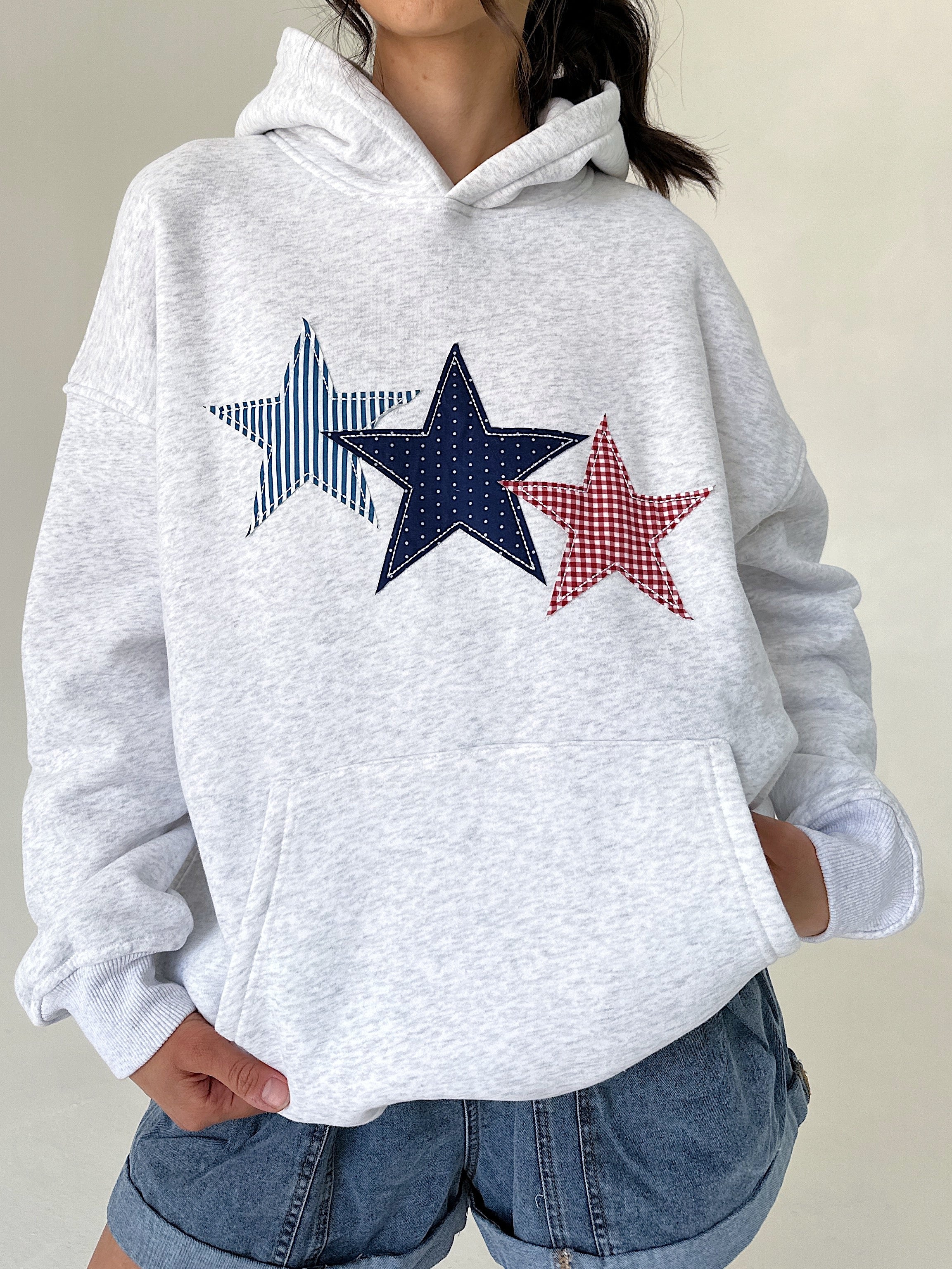 Person wearing a gray hoodie with star designs on a plain background