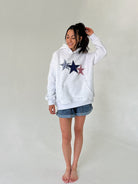 Person wearing a grey hoodie with star designs on a plain background