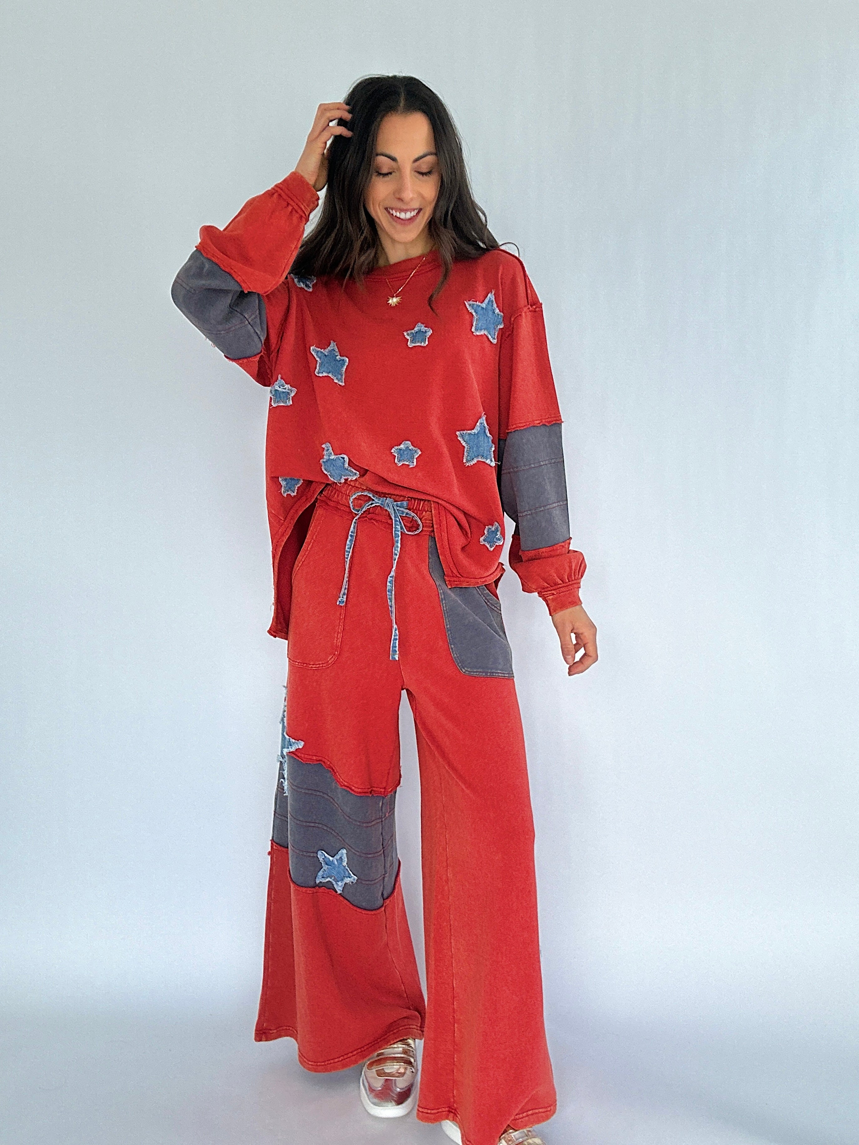 Woman wearing a red and gray terry knit outfit with star patches on a white background