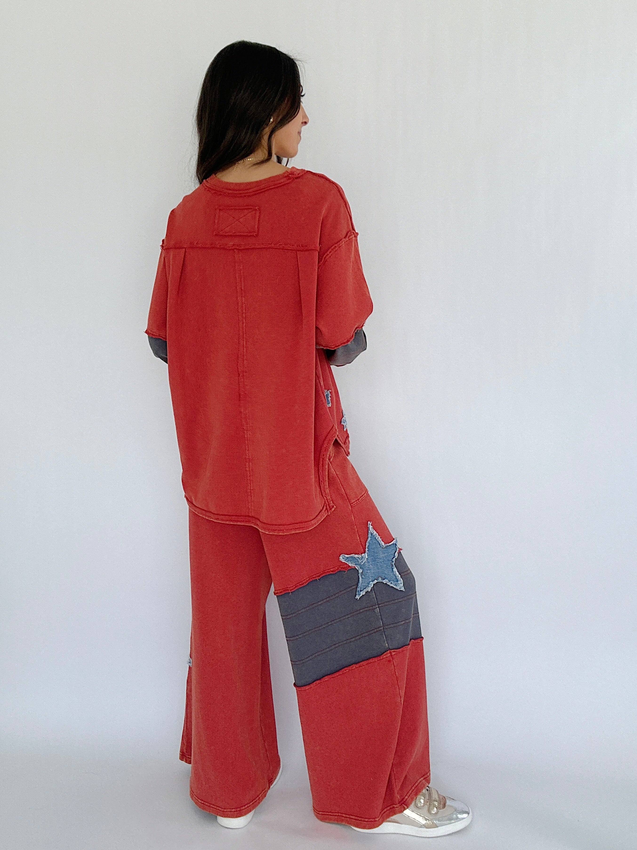 Person wearing a red outfit with a star patch on a plain background from the back