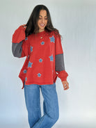 Woman wearing a red sweater with star patterns and blue jeans on a white background