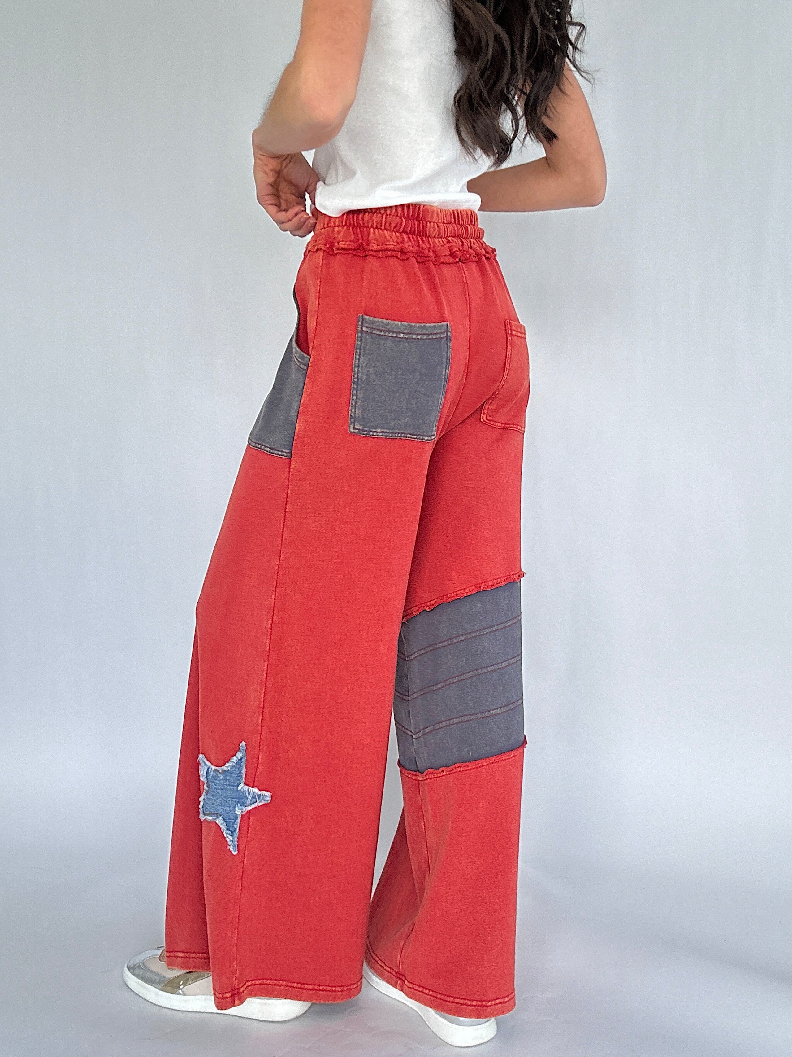 Red and gray patchwork pants with a star design on a white background showing back pockets