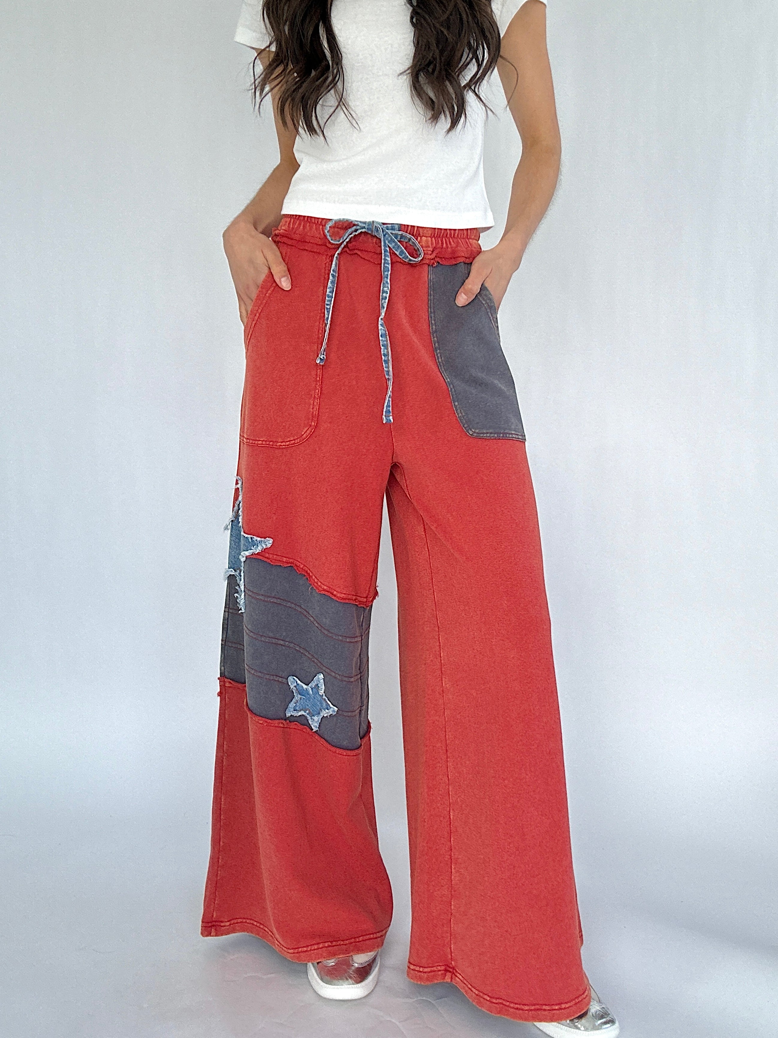 Red and gray patchwork pants worn by a person on a white background
