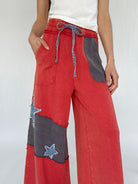 Red patchwork pants with gray patches on a white background showing elastic drawstring waist