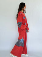 Woman wearing a red outfit with star patterns against a white background from side