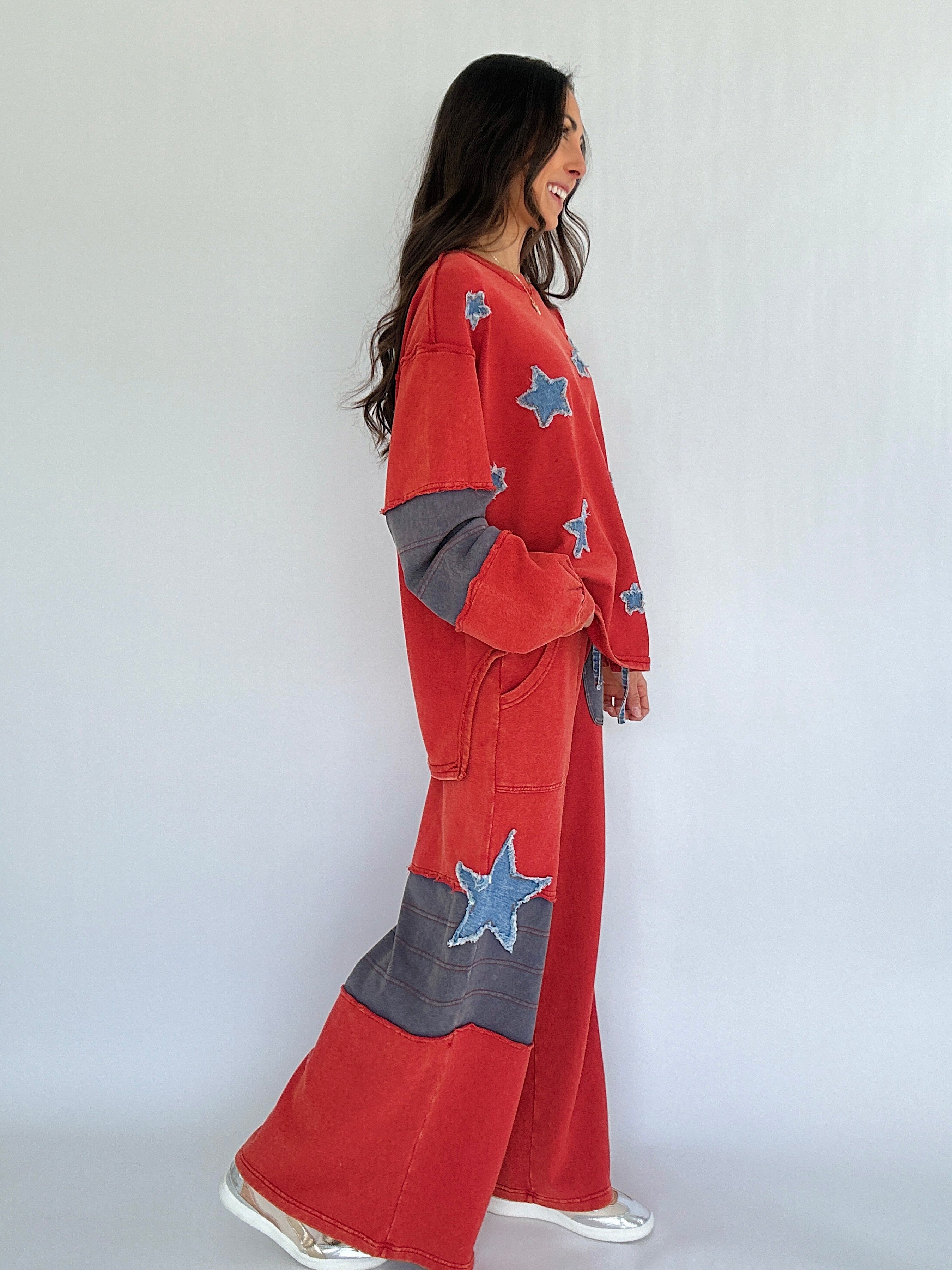 Woman wearing a red outfit with star patterns against a white background from side