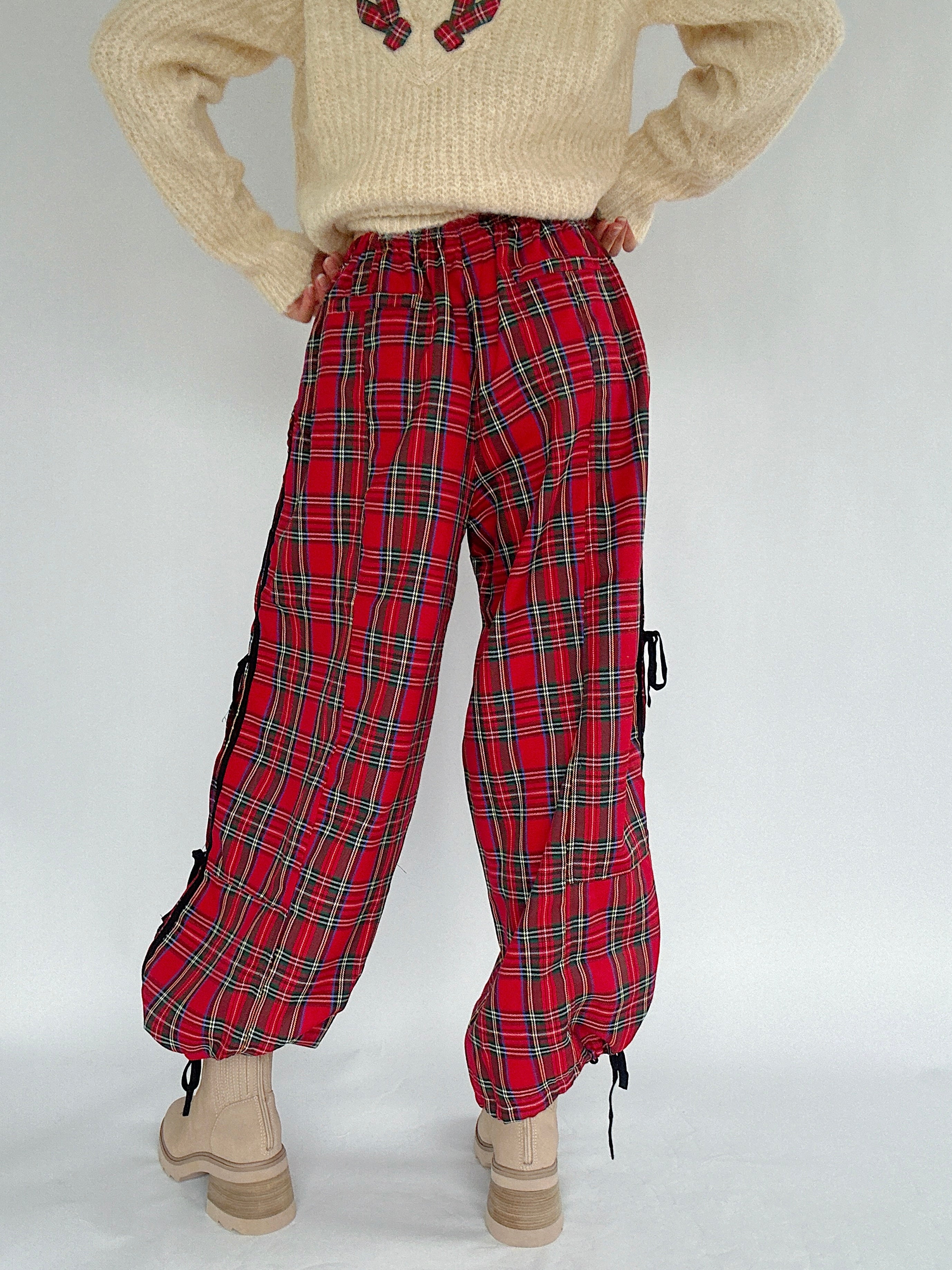 Red plaid pants worn with a beige sweater on a white background showing back