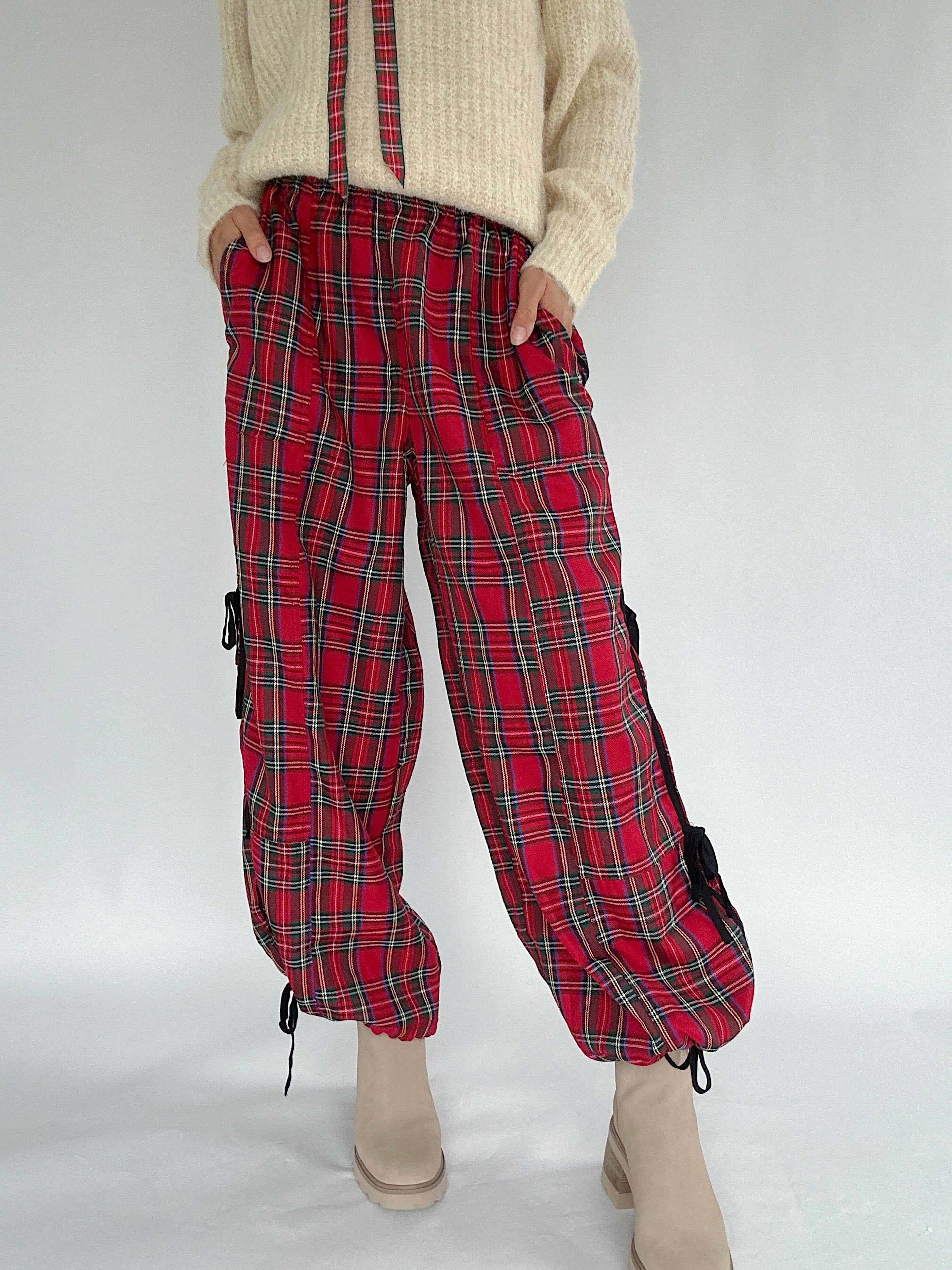Red plaid pants worn with a beige sweater on a white background