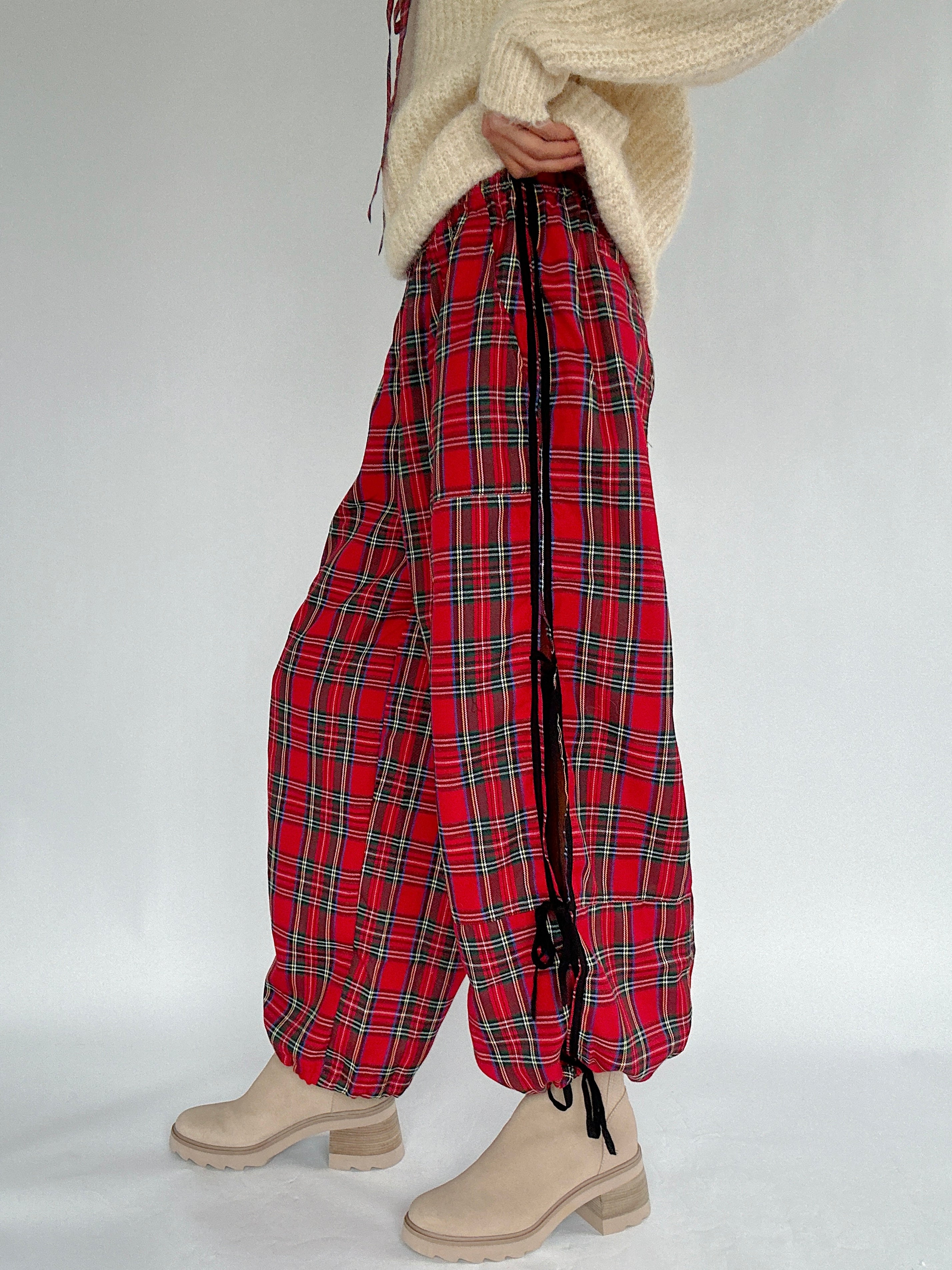 Red plaid pants worn with a beige sweater on a plain background