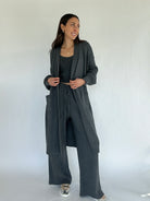 Woman wearing a gray outfit with a matching cardigan and pants against a white background