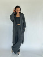 Woman wearing a gray knit outfit with a long cardigan on a white background