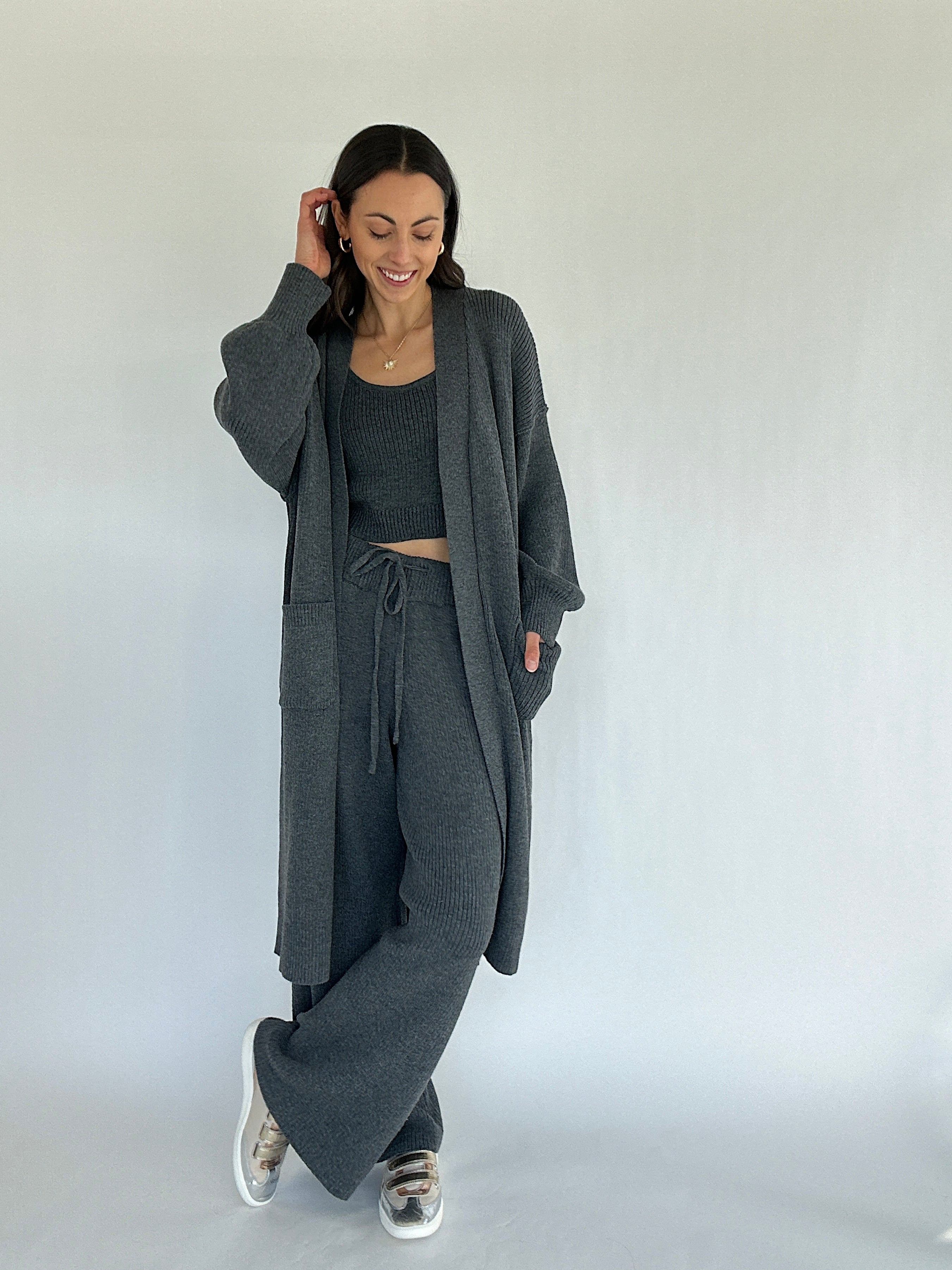 Woman wearing a gray outfit with a long cardigan on a white background