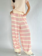 Person wearing pink and white striped pants with a matching top on a plain background