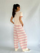 Woman wearing a striped outfit with a white background showing the back