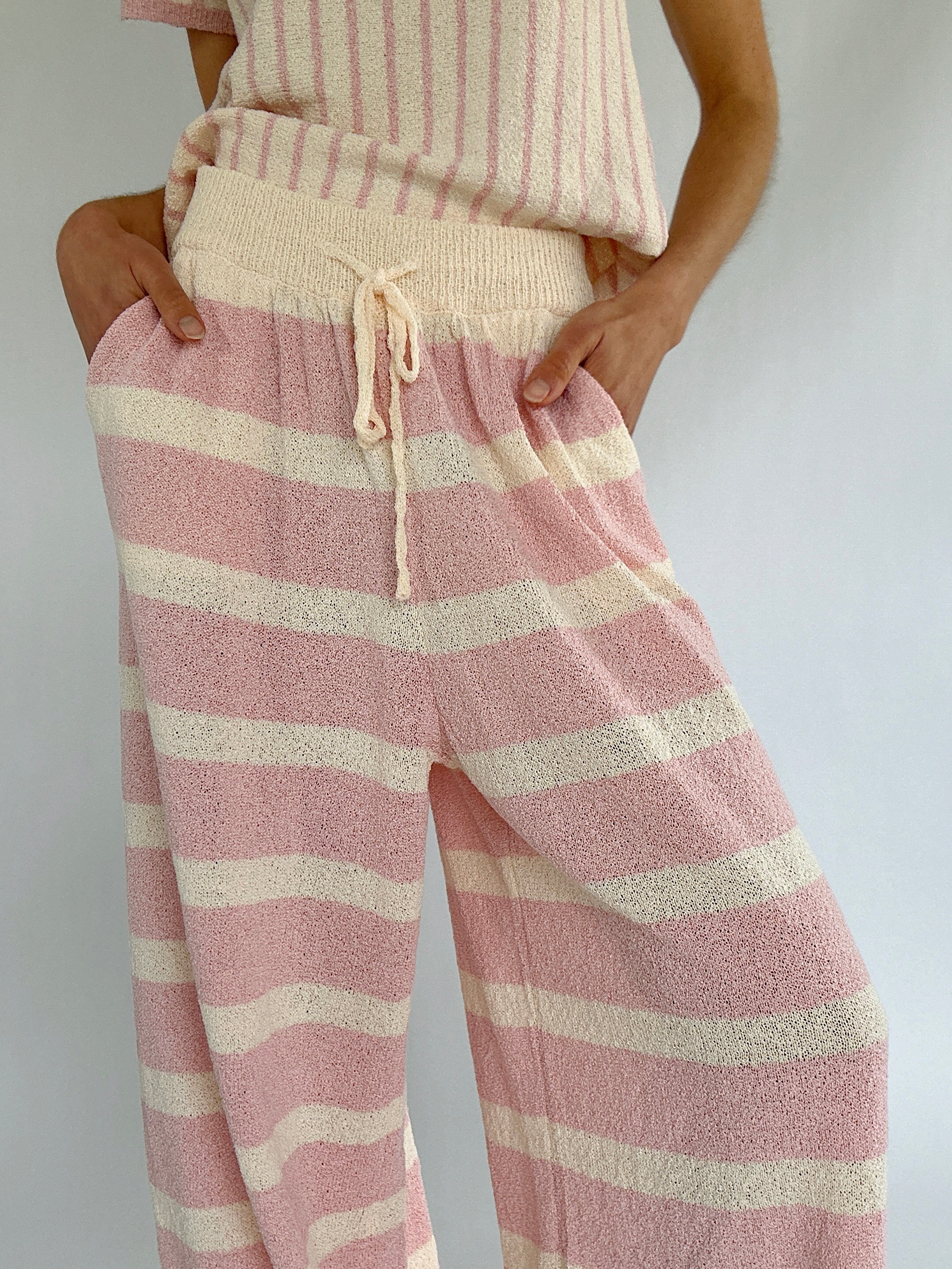 Pink and cream striped pants worn by a person on a plain background