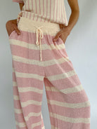 Pink and cream striped pants worn by a person on a plain background