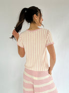 Woman wearing a pink and white striped outfit against a plain background showing back