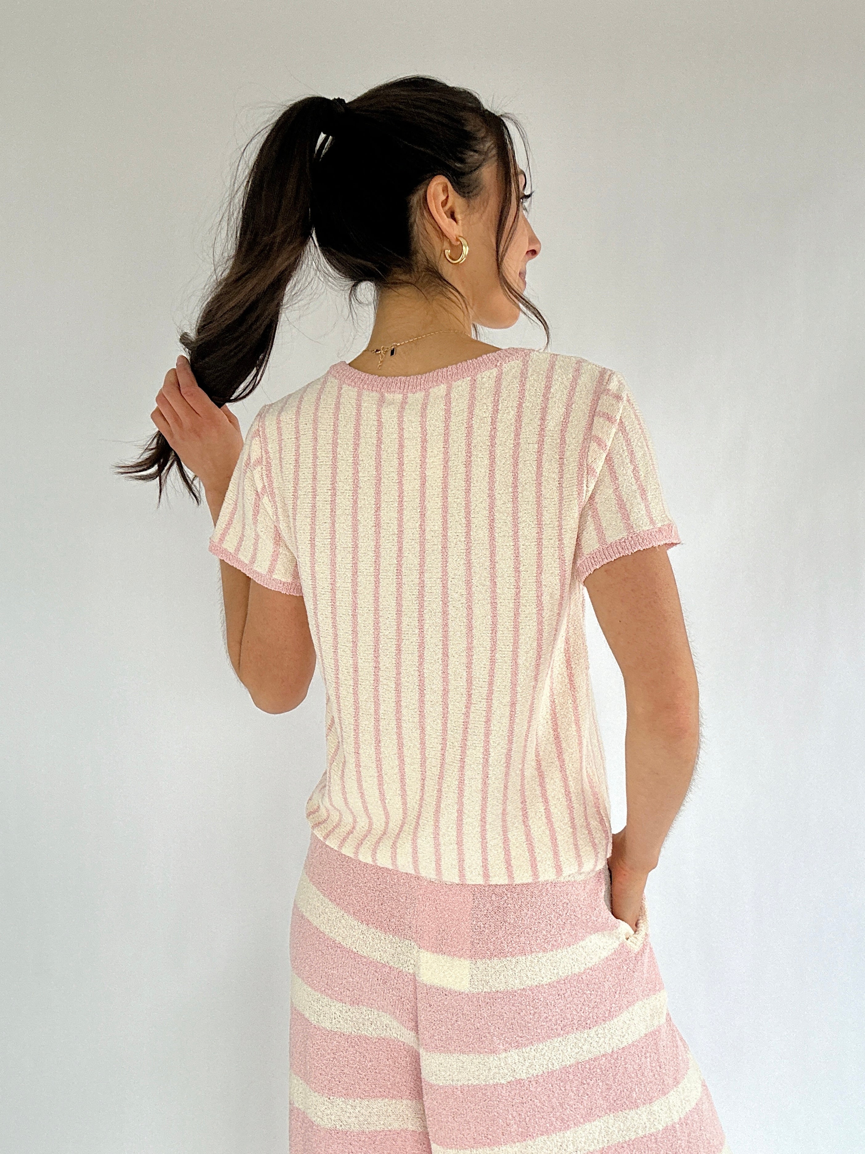 Woman wearing a pink and white striped outfit against a plain background showing back