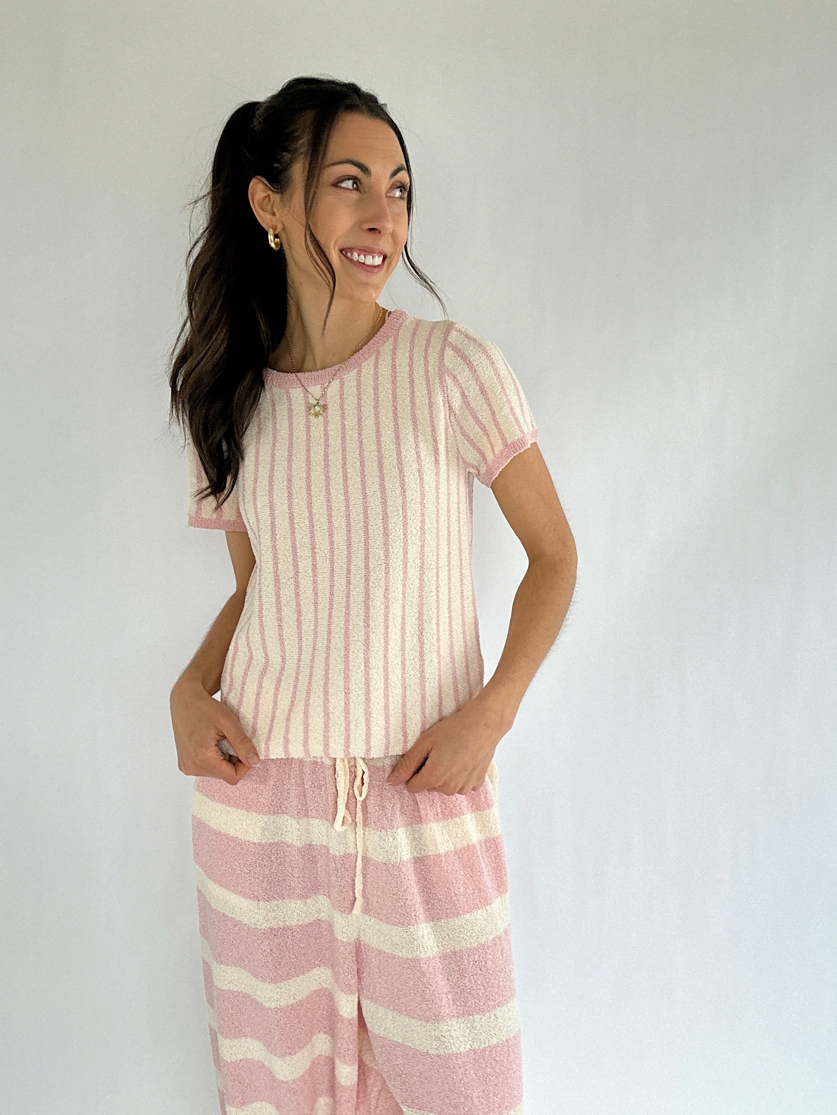 Woman wearing a pink and white striped outfit against a plain background