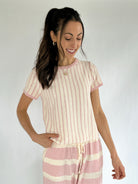 Woman wearing a pink and white striped outfit against a plain background