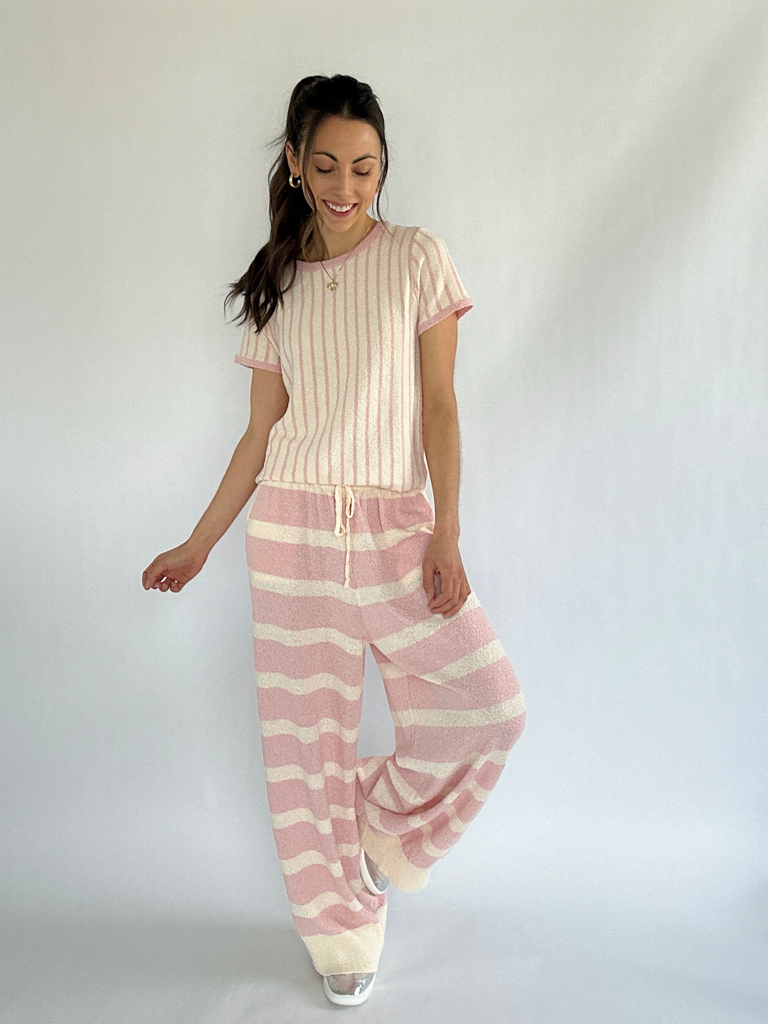 Woman wearing a pink and white striped outfit on a plain background