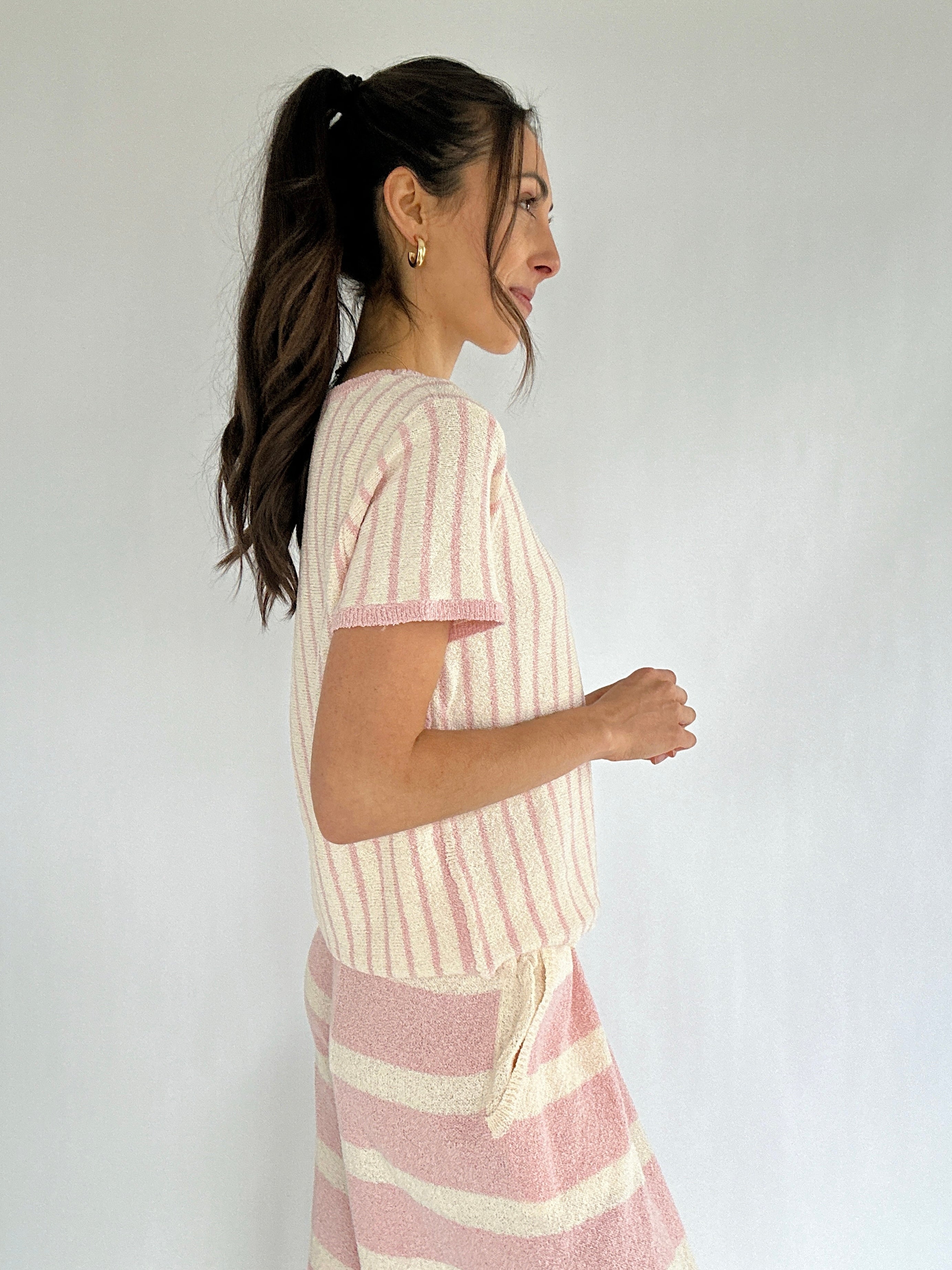 Woman wearing a pink and white striped outfit against a plain background