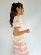 Woman wearing a pink and white striped outfit against a plain background