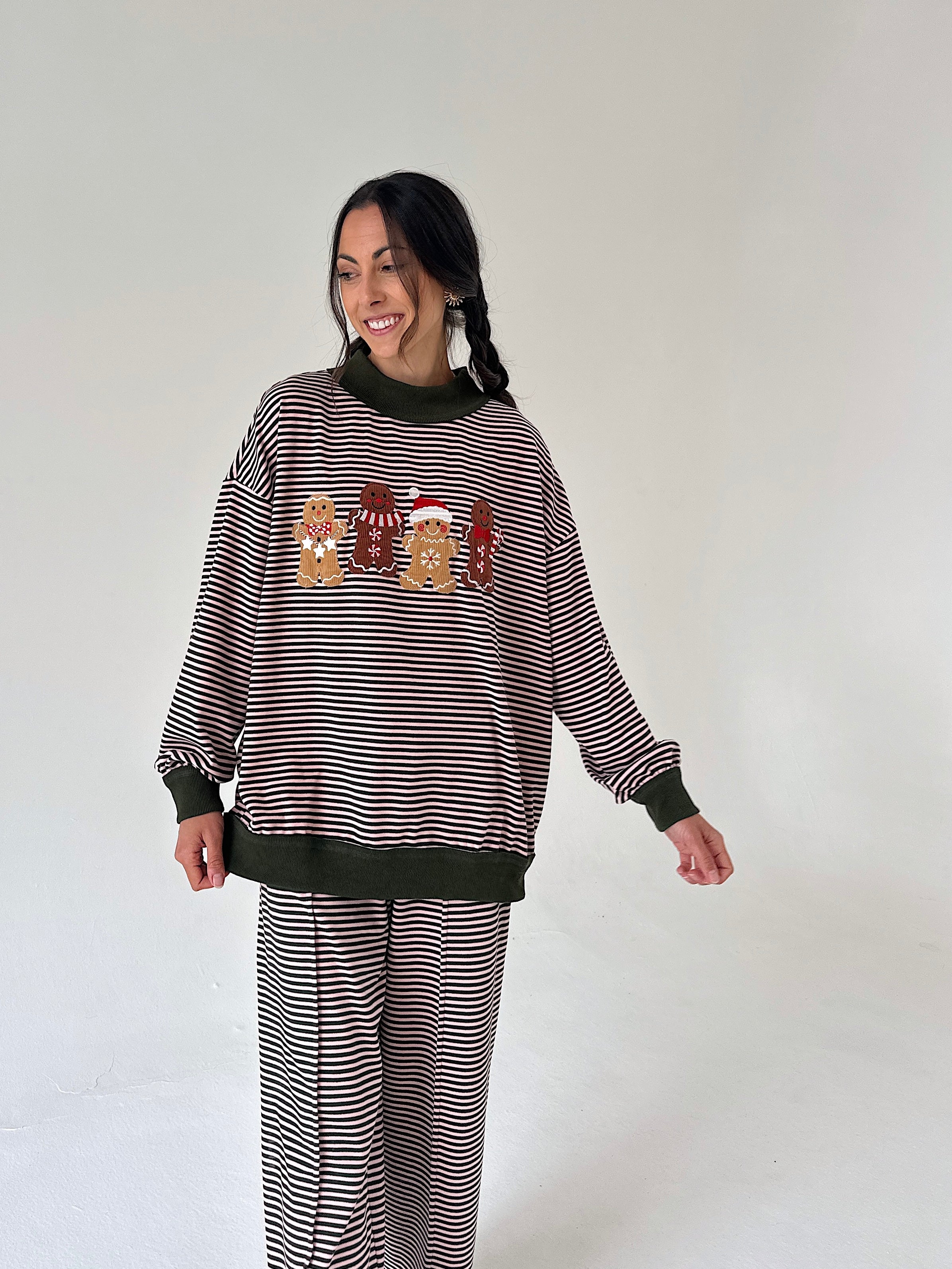 A woman modeling a matching holiday-themed sweatshirt and sweatpants set. The set features thin horizontal stripes with solid dark brown ribbed trim at the crew neck, cuffs, and hem.