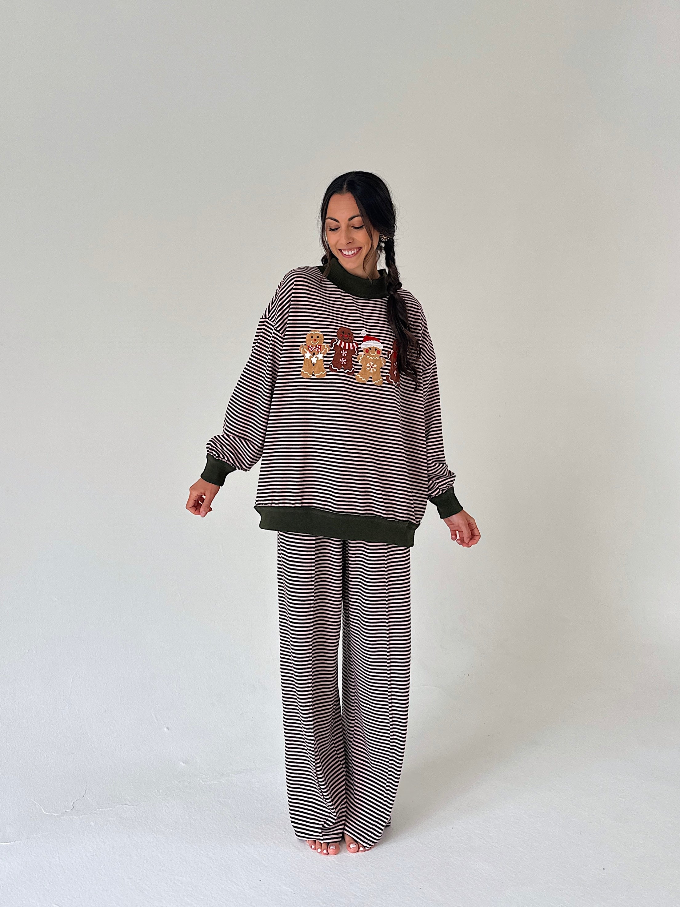 A woman modeling a matching two-piece loungewear set consisting of a long-sleeve sweatshirt and wide-leg pants. The set features horizontal stripe pattern with a small colorful graphic on the chest.