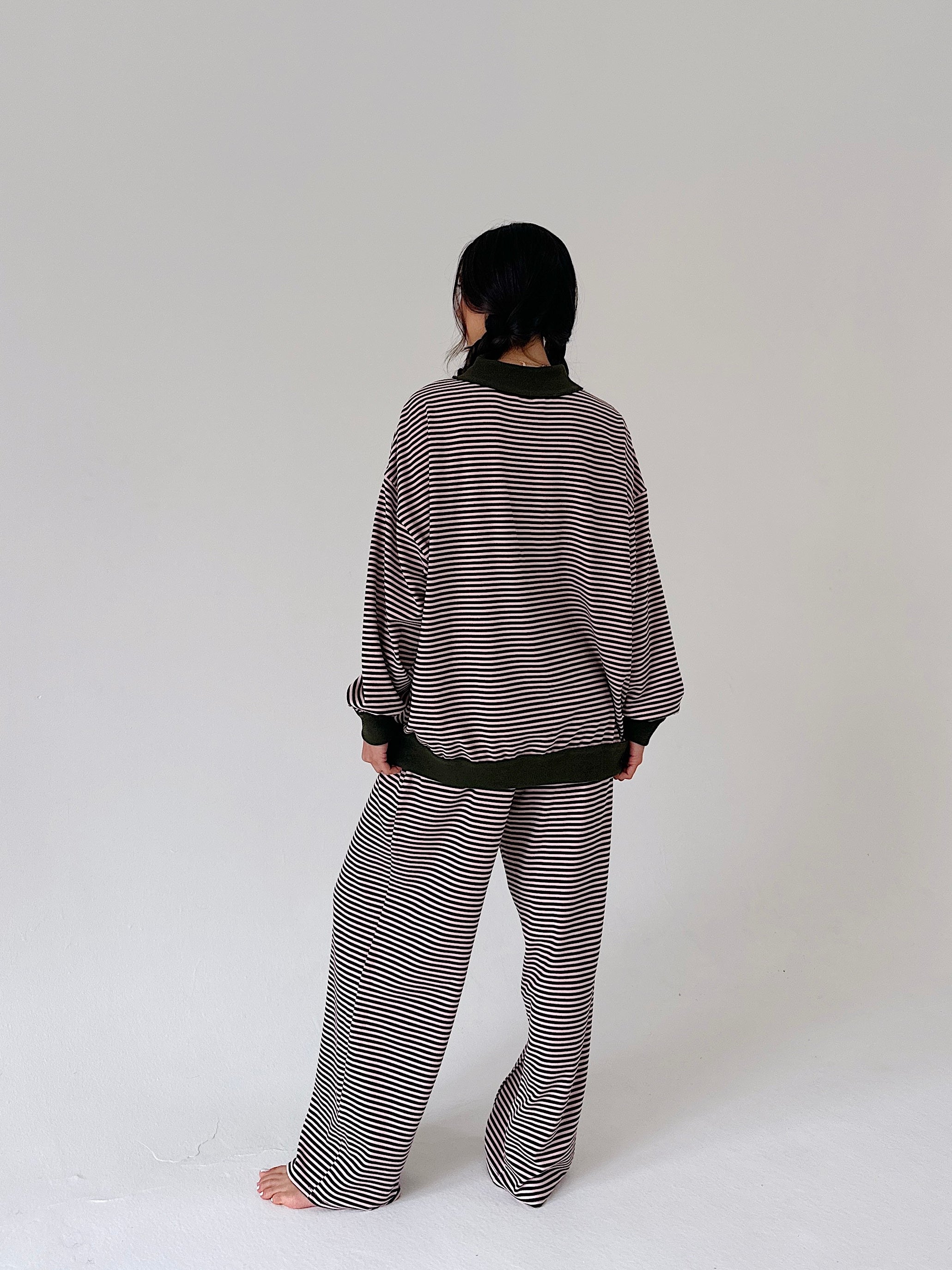 A person shown from the back wearing a matching striped lounge set consisting of a long-sleeve top and wide-leg pants, photographed against a plain light gray studio background.