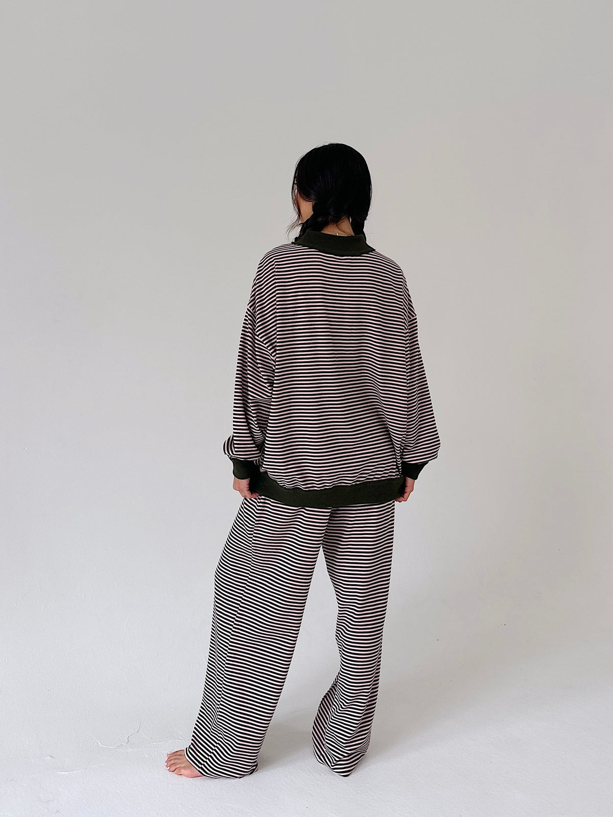 A person shown from the back wearing a matching striped lounge set consisting of a long-sleeve top and wide-leg pants, photographed against a plain light gray studio background.