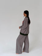 A woman modeling a matching two-piece loungewear set consisting of a long-sleeve top and wide-leg pants, both featuring a black and white horizontal stripe pattern with solid black ribbed trim.