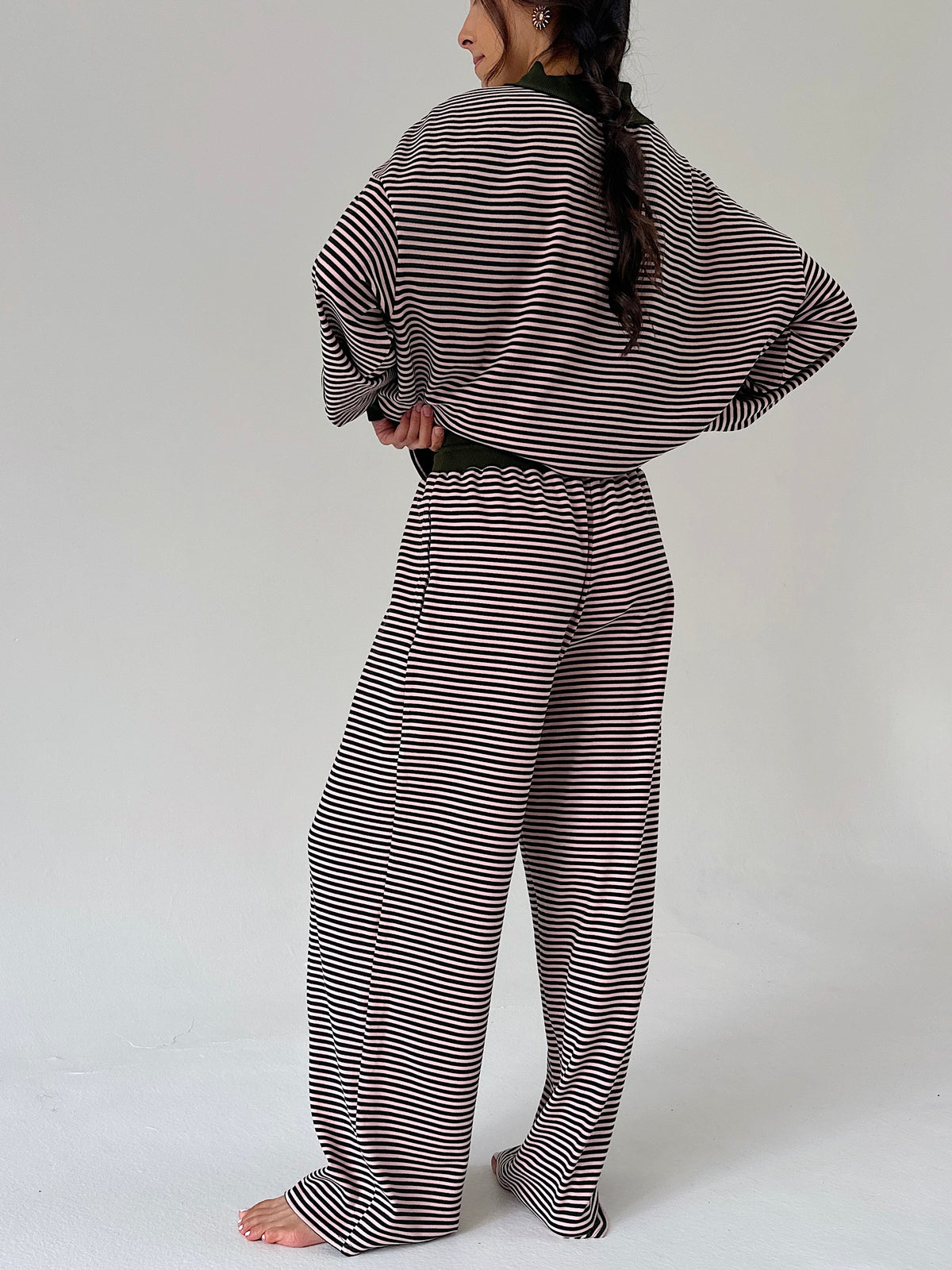 A woman shown from the back wearing a matching two-piece loungewear set with horizontal stripes, consisting of a long-sleeve top and wide-leg pants, against a plain light gray studio background.