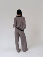 A person shown from the back wearing a matching striped knit top and wide-leg pants set, standing against a plain light gray studio background.