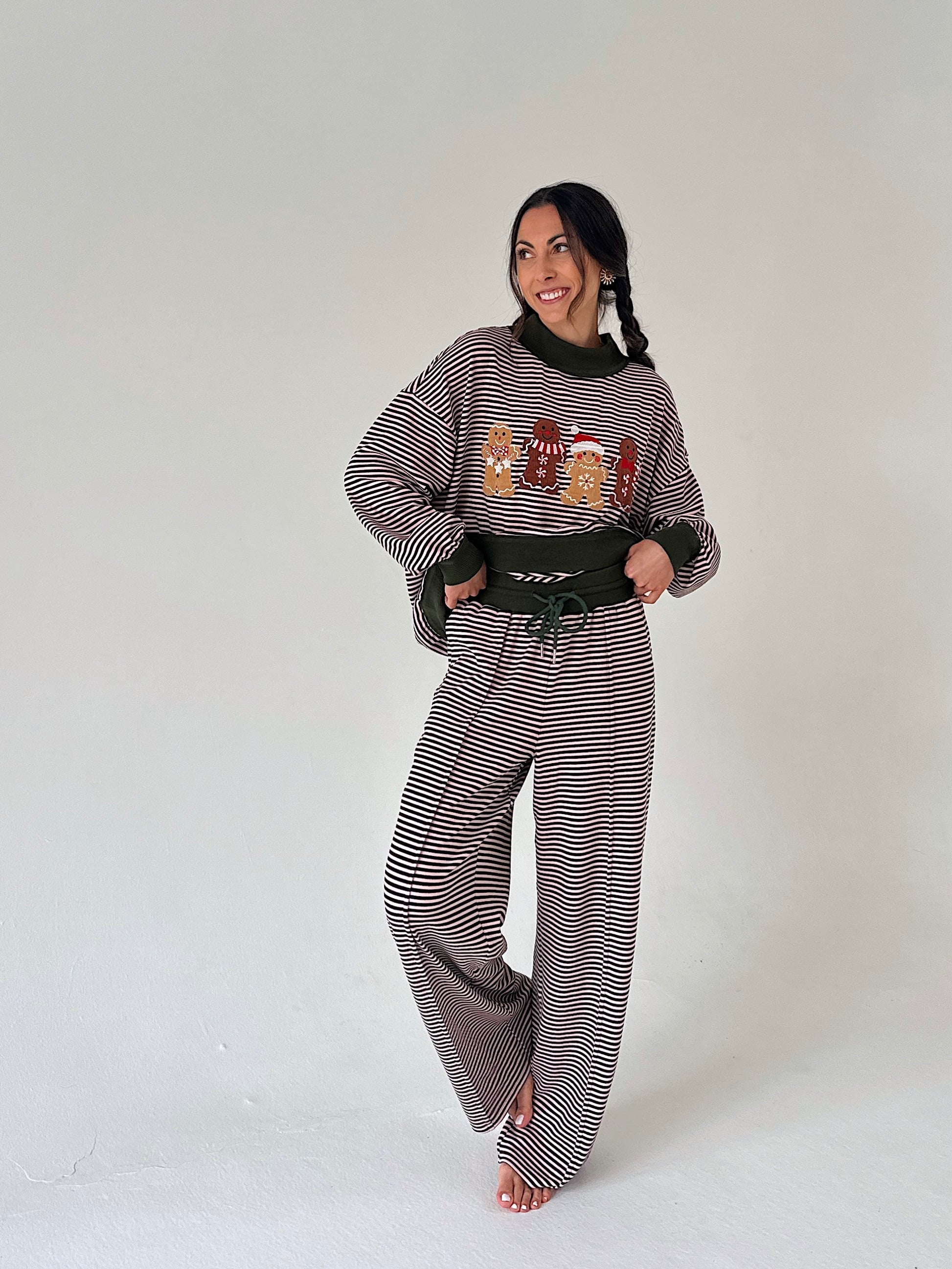 A woman modeling a matching two-piece loungewear set consisting of a long-sleeve sweatshirt and wide-leg pants, both featuring a striped pattern. The sweatshirt has a graphic print of cartoon characters on the front.
