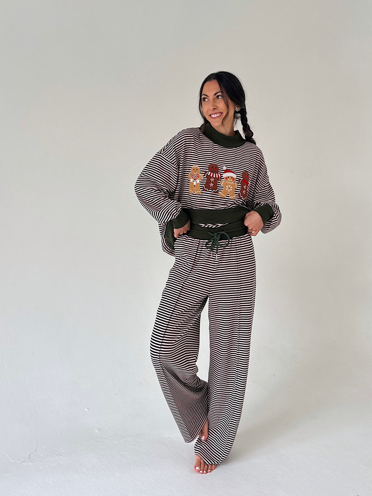 A woman modeling a matching two-piece loungewear set consisting of a long-sleeve sweatshirt and wide-leg pants, both featuring a striped pattern. The sweatshirt has a graphic print of cartoon characters on the front.