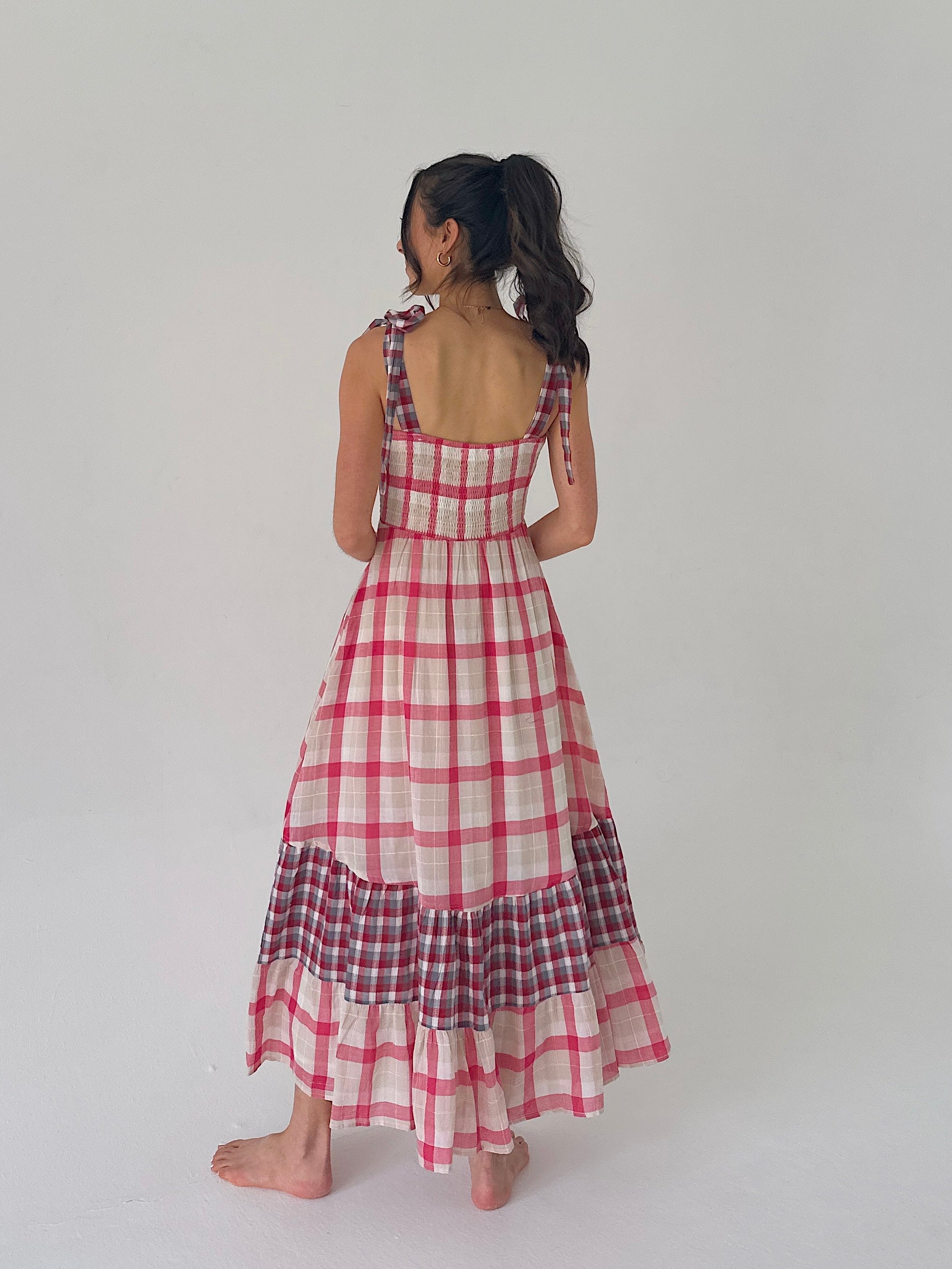 Woman wearing a red and white checkered dress on a plain background showing back