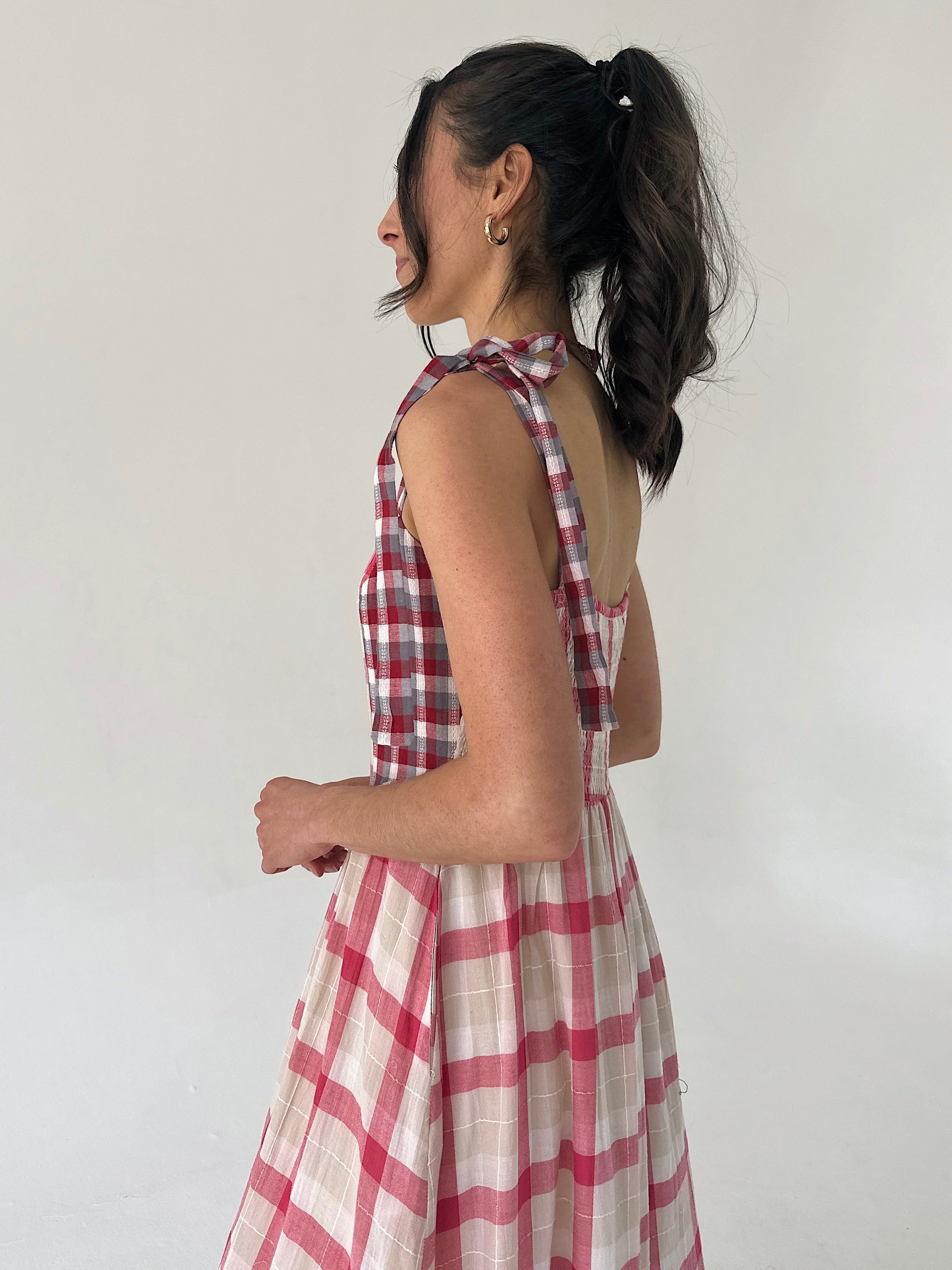 Woman wearing a red and white checkered dress against a plain background