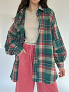 Person wearing a plaid shirt over a beige top and red pants against a white background