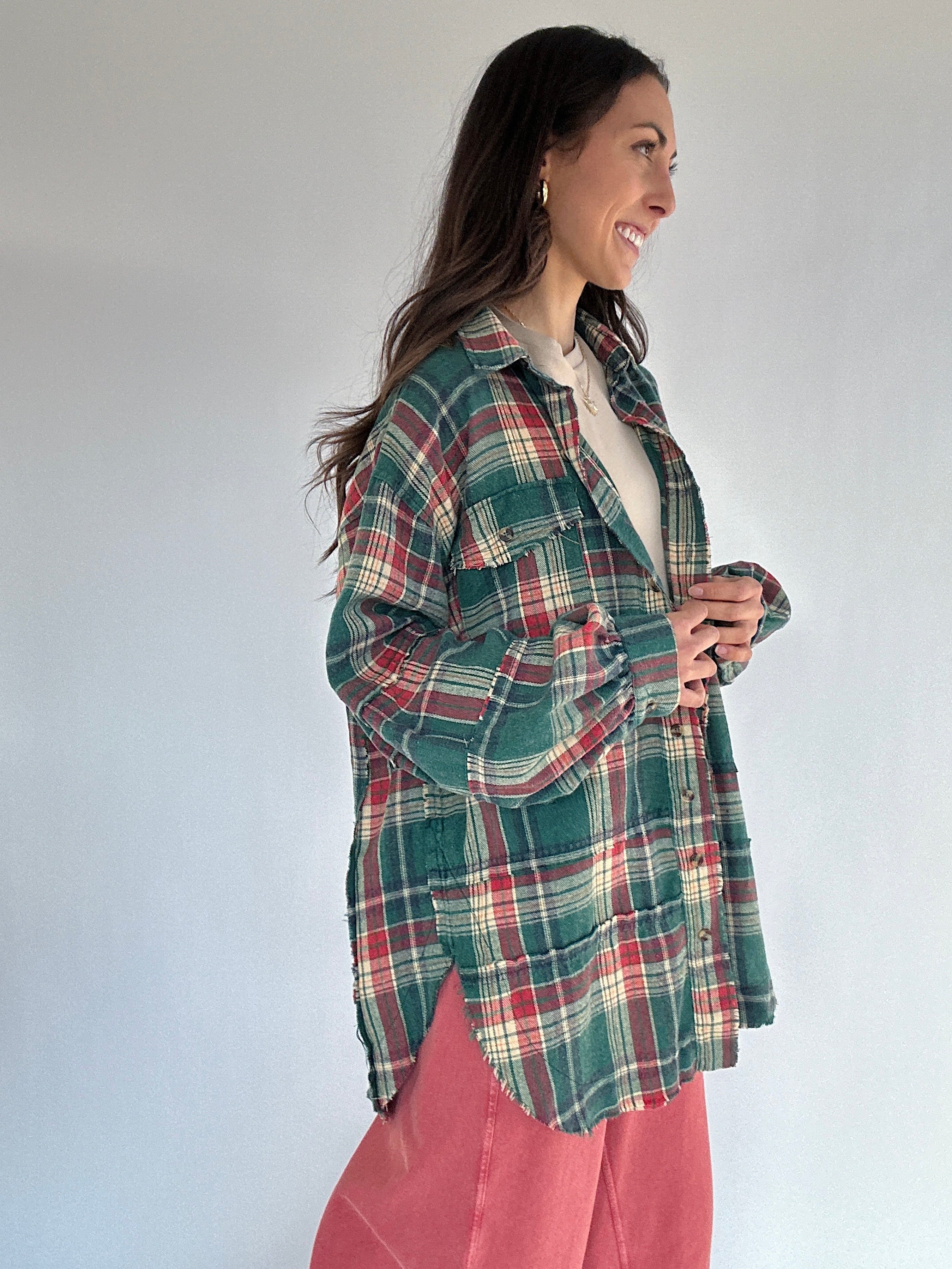 Woman wearing an oversized green plaid shirt and red pants against a white background from side