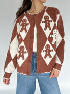 Person wearing a brown and white patterned sweater with gingerbread men design.